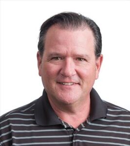 A person smiles at the camera with short brown hair, a striped shirt, and white background