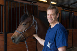 Dave Frisbie smiling with a brown horse