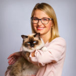 blond woman with glasses holding a brown and white cat