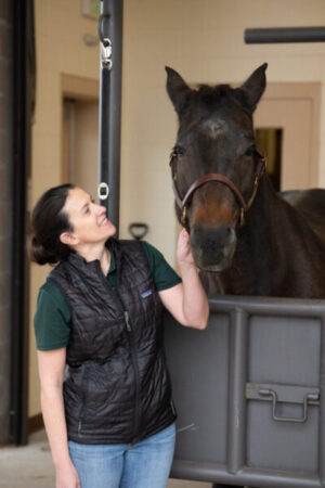 woman looking up at a brown horse's face